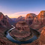 Panoramic view of Zion National Park at sunset with towering cliffs and a hiker