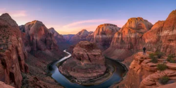 Panoramic view of Zion National Park at sunset with towering cliffs and a hiker